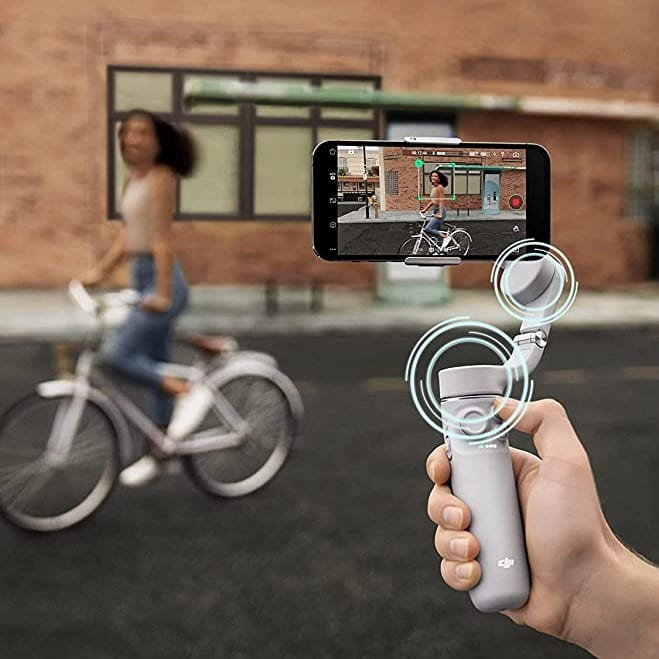 photo showing a mobile phone mounted in a DJI gimbal stabilizer, shooting a video of a girl riding a bicycle